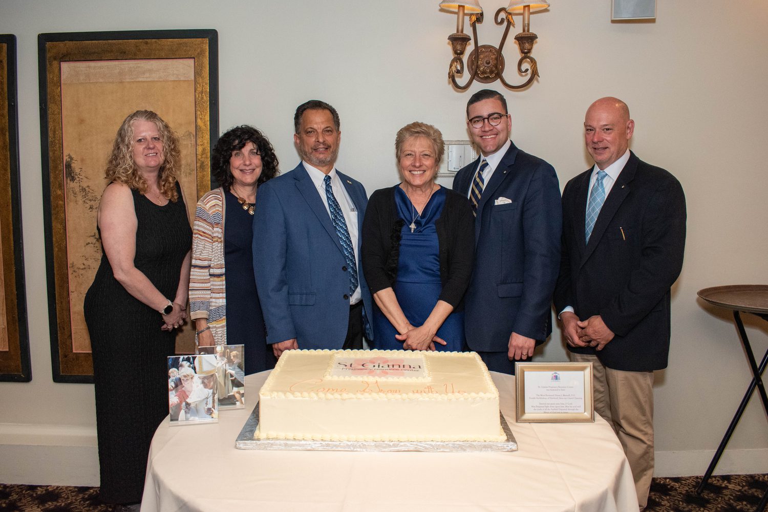 The Board of Directors gathered behind the Come Grow With Us cake